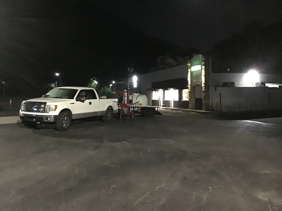 Trailer-mounted pressure washing rig at a nighttime commercial cleanup
